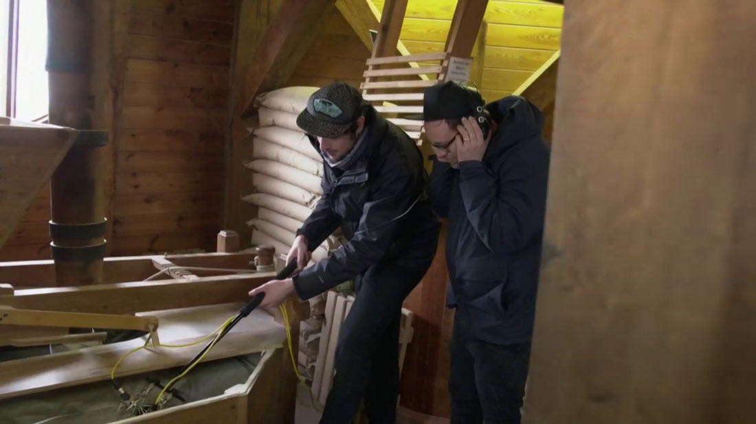 Two participants with headphones and a directional microphone in a wood workshop
